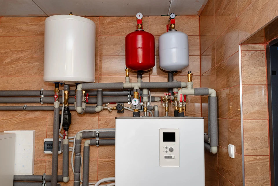 Technicien en combinaison bleue installant un radiateur blanc à panneaux dans un intérieur résidentiel