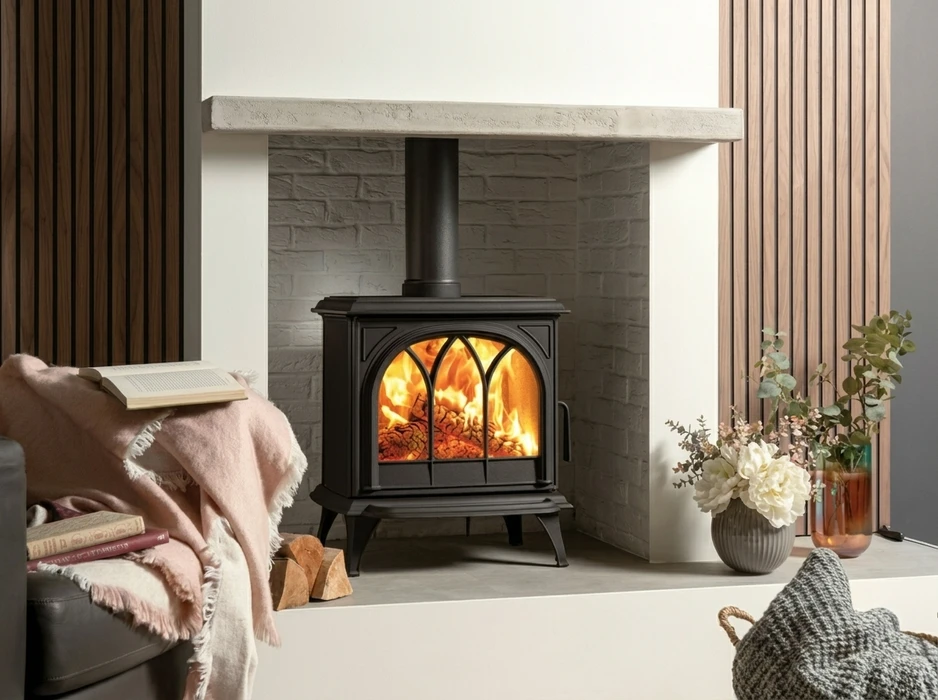 Intérieur cosy avec poêle à bois en fonte noire, design gothique à arches trilobées, vitré, pieds ornementaux